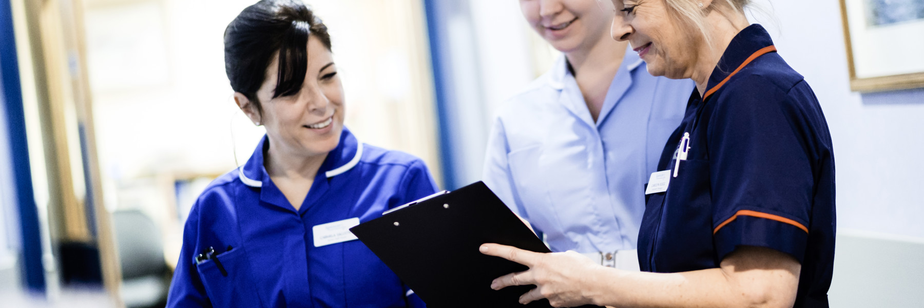 A collection of nurses examine a clipboard.
