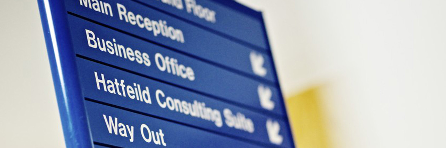 A close up of a blue informational sign in a hospital, directing to areas of the building.